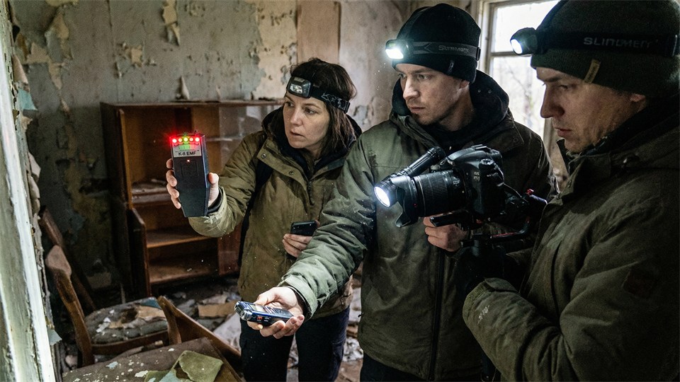 Ghost hunters use measuring equipment in a dark room