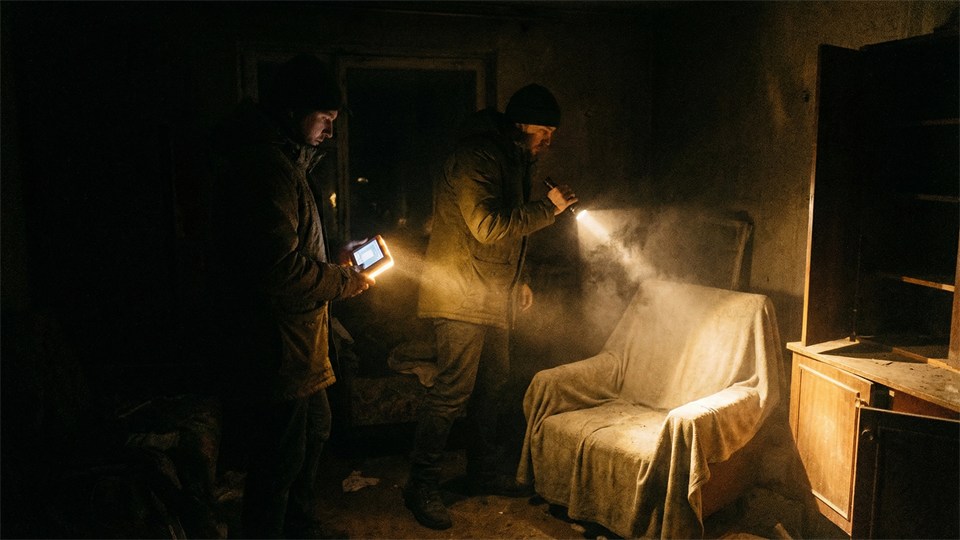 Zwei Personen untersuchen einen dunklen Raum mit Taschenlampe