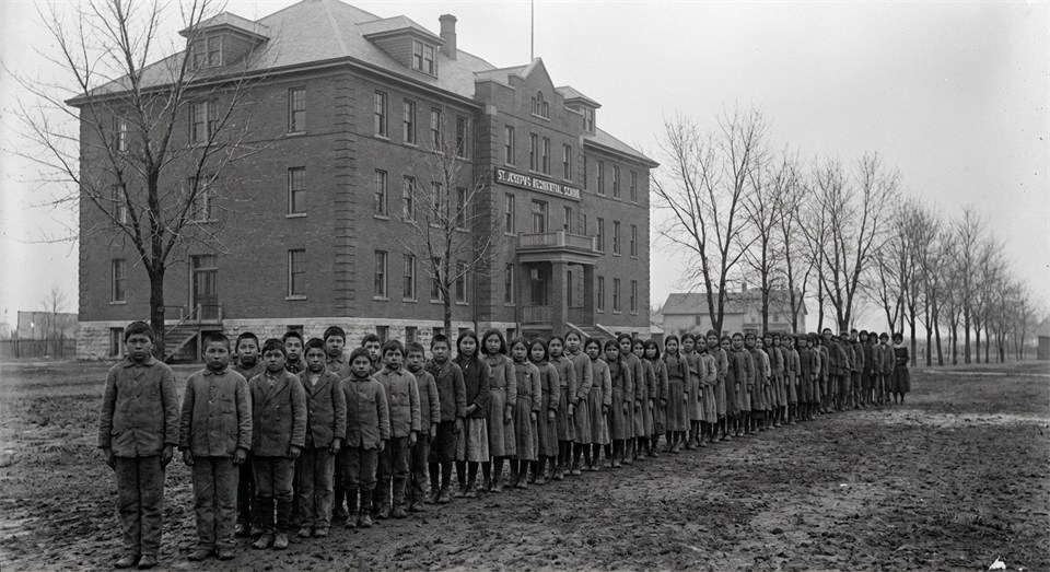 Kanadische Residential School, Kinder stehen in einer Reihe vor einem Gebäude