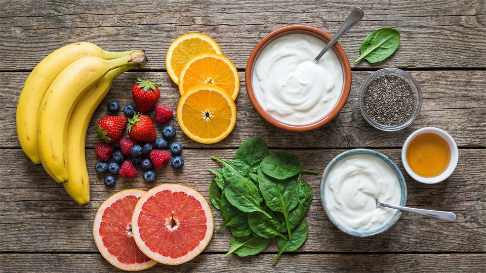 Smoothie-ingredienser: banan, bær, citrus og grøntsager lagt op på et bord