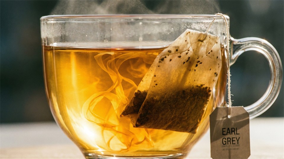 Et tebrev der trækker i en kop, tæt på, med gylden væske