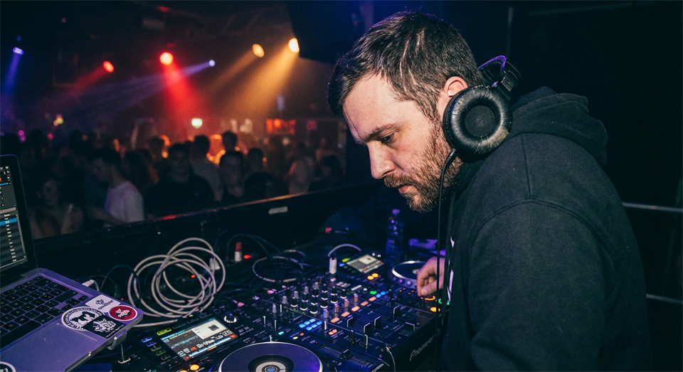 DJ med hovedtelefoner der lytter til cue-lyd under mixing